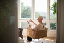 Donna anziana relax e lettura libro in poltrona soggiorno — Foto stock