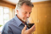Крупним планом безтурботний чоловік пахне і дегустує червоне вино — стокове фото