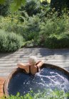 Donna anziana rilassante nella vasca idromassaggio sul soleggiato patio estivo — Foto stock
