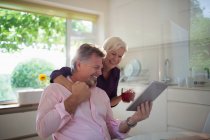 Felice coppia anziana utilizzando tablet digitale in cucina — Foto stock