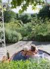 Безтурботний пара розслабляється в гарячій ванні на сонячному літньому патіо — стокове фото