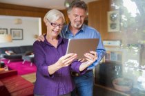 Glückliches Senioren-Paar nutzt digitales Tablet im Wohnzimmer — Stockfoto