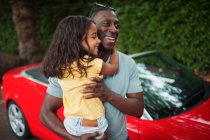 Счастливый отец держит дочь снаружи кабриолета — стоковое фото