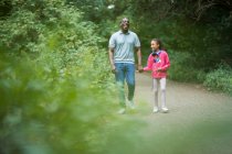 Happy father and daughter holding hands on path in woods — Stock Photo
