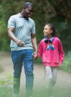 Щасливий батько і дочка тримають руки, ходячи на парковій доріжці — стокове фото