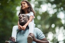 Feliz padre llevando a la hija en hombros - foto de stock