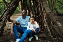 Heureux père et fille relaxant à l'intérieur arbre branche tipi dans bois — Photo de stock