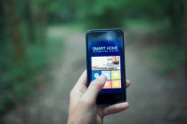 Feche o aplicativo de automação doméstica POV na tela do telefone inteligente — Fotografia de Stock