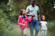 Щасливий батько і доньки тримають руки, ходять на парковій доріжці — стокове фото