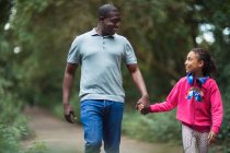 Happy father and daughter holding hands walking on park path — Stock Photo
