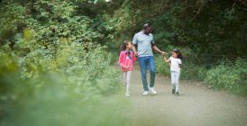 Отец и дочери держатся за руки на дорожке в парке — стоковое фото