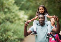 Father carrying daughter on shoulders on path in woods — Stock Photo