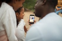 Family video chatting with grandparents on smart phone screen — Stock Photo