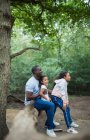 Feliz pai e filhas sentados no tronco caído na floresta — Fotografia de Stock
