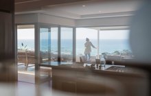 Woman looking at sunny ocean view on luxury home showcase balcony — Fotografia de Stock