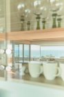 Reflection of sunny ocean view in kitchen cabinet with glassware - foto de stock