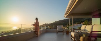 Woman with white wine enjoying sunset ocean view on luxury balcony — Foto stock