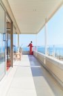 Frau in Kleid genießt sonnigen Meerblick vom Luxus-Balkon — Stockfoto