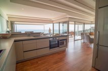 Maison moderne vitrine cuisine intérieure avec vue sur l'océan ensoleillé — Photo de stock