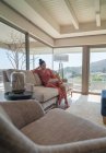 Frau entspannt mit digitalem Tablet auf Sofa im Luxus-Wohnzimmer — Stockfoto
