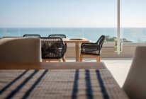 Meerblick hinter Esstisch und Stühlen auf sonnigem Luxus-Patio — Stockfoto