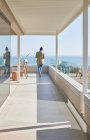 Woman on sunny luxury home showcase balcony with ocean view — Stock Photo