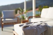 Blanket and magazine on sunny patio sofa — Stock Photo
