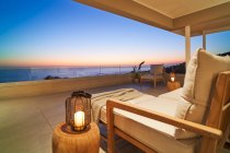Lanterne et fauteuil sur patio de luxe avec vue panoramique sur l'océan coucher de soleil — Photo de stock