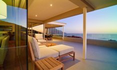 Chaise Lounge на розкішному дворику з видом на океан заходу сонця — стокове фото