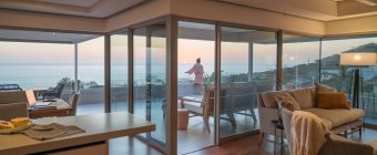Donna godendo vista panoramica sull'oceano tramonto sul balcone di lusso — Foto stock