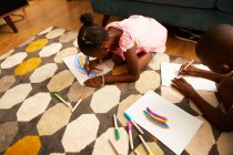 Menina desenho arco-íris multicolorido com marcadores na sala de estar tapete — Fotografia de Stock