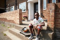 Portrait confident boy with skateboard on sunny front stoop — Stock Photo