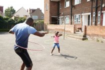 Padre e figlia che giocano con cerchi di plastica nel quartiere soleggiato — Foto stock