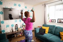 Frau mit Kurzhanteln übt online im Wohnzimmer — Stockfoto