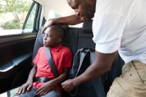 Батько кріпиться ремінь безпеки для сина на задньому сидінні автомобіля — стокове фото