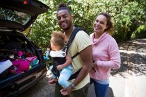 Portrait happy couple with baby daughter outside car — Stock Photo