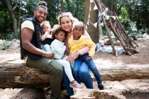 Porträt glückliche, liebevolle Familie auf umgestürzten Baumstämmen im Wald — Stockfoto