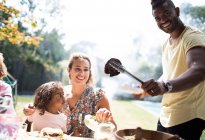 Retrato família feliz desfrutando churrasco no quintal ensolarado — Fotografia de Stock