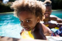 Portrait cute girl with curly hair in sunny summer swimming pool — Stock Photo