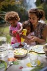 Mãe e filhas desfrutando de churrasco no quintal de verão à mesa — Fotografia de Stock