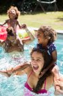 Feliz familia juguetona en la soleada piscina de verano - foto de stock