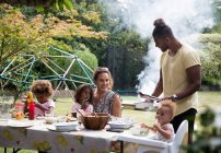 Felice famiglia godendo barbecue estivo al tavolo patio — Foto stock