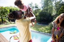 Glückliche Familie spielt am sonnigen Sommerpool — Stockfoto