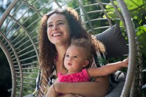 Счастливая мать держит дочь в солнечном патио — стоковое фото