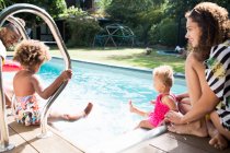 Happy family relaxing and splashing at sunny summer swimming pool — Stock Photo