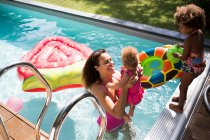 Mother and daughters playing in sunny summer swimming pool — Stock Photo