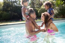 Pais brincalhões jogando frango com filhas nos ombros na piscina — Fotografia de Stock