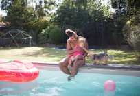 Padre e hija pequeña con perro en la piscina de verano - foto de stock