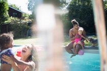 Родина відпочиває і грає в сонячному літньому басейні на задньому дворі — стокове фото