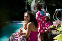 Ritratto felice madre e figlia godendo ghiaccio aromatizzato a bordo piscina — Foto stock